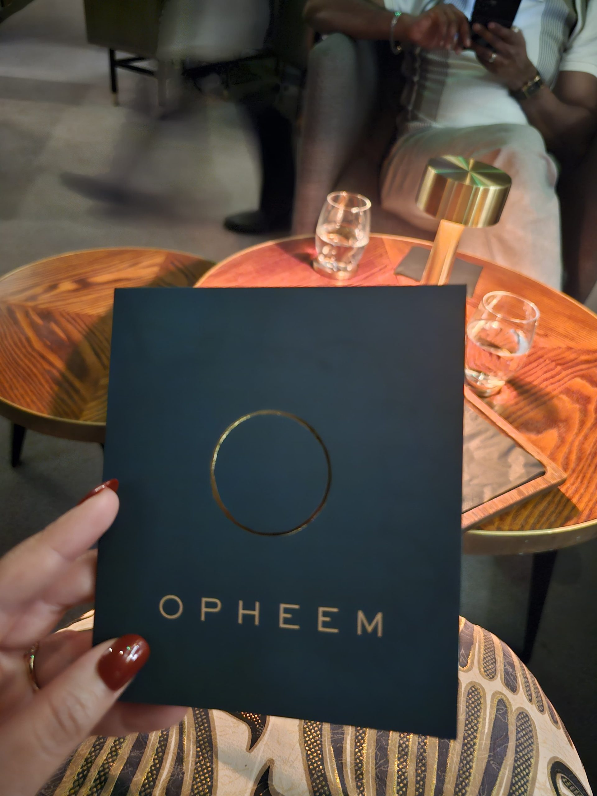 Holding the Opheem menu cover with its gold ring logo at the table
